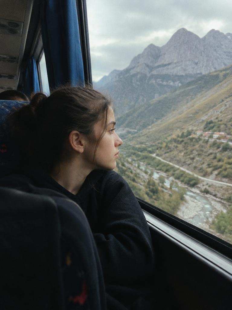 A teenager looking out of a bus window at the mountains of northern Albania