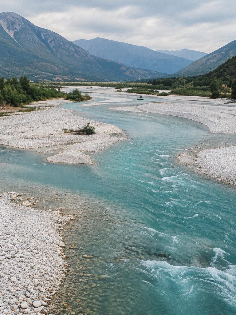 The turquoise braided Vjosa river flowing between pale gravel banks